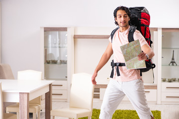 Young male tourist preparing for trip at home
