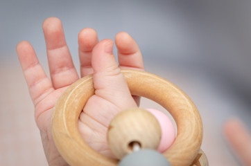 Close-up of a baby´s hand, playing with a wooden toy.