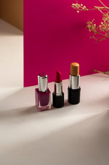 lipstick, Concealer bar and nailpolishes on modern pink background. Product and cosmetics