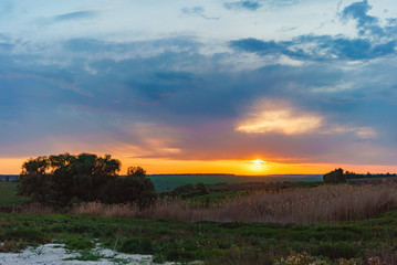 Evening orange sunset over Valday lake, Russia nature landscape photography. Autumn sunset, outdoor nature of Russia. Fantastic sunset over lake near green meadow. Autumn nature sunset, Russia