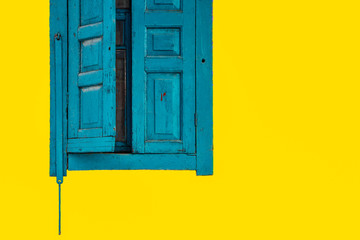 Old wooden windows, blue curtains on a yellow background