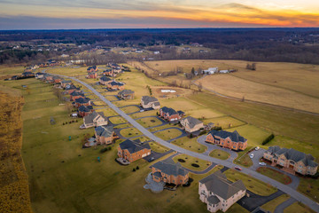 Obraz premium Aerial sunset view of American luxury traditional, contemporary single family home estates with gable roof, in a new residential suburban neighborhood, for upper middle class families in the USA