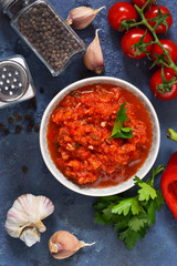 Tomato sauce with peppers, spices and herbs on the kitchen table. View from above.