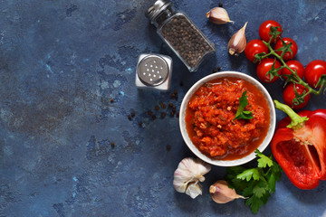 Tomato sauce with peppers, spices and herbs on the kitchen table. View from above.