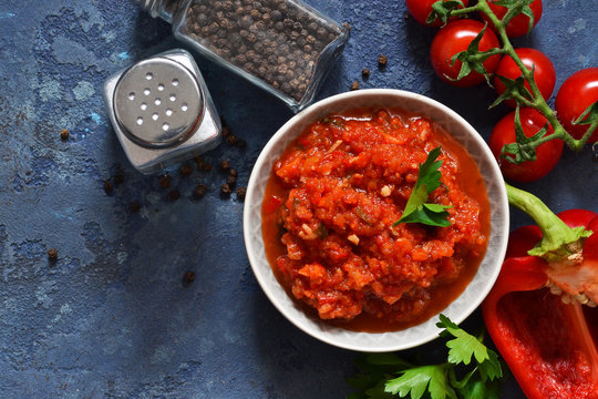 Tomato sauce with peppers, spices and herbs on the kitchen table. View from above.