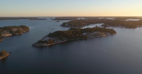 Drone shot, towards frosty and snowy islands, on the gulf of Finland, at sunset, on a sunny, cold, autumn evening, Varsinais-suomi, Finland