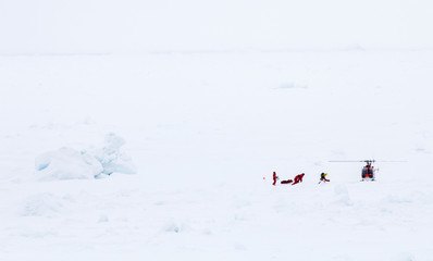 Scientists over an ice floe for research are evacuated by helicopter