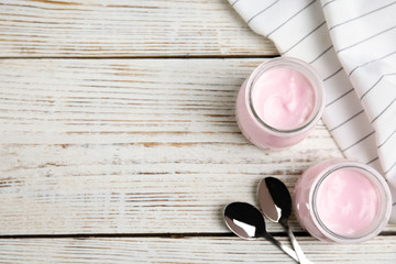 Flat lay composition with creamy yogurt and space for text on white wooden background