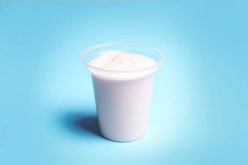 Plastic cup with creamy yogurt on color background