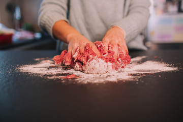 a person kneading minced meat in a beautiful kitchen