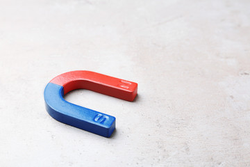 Red and blue horseshoe magnet on grey background. Space for text