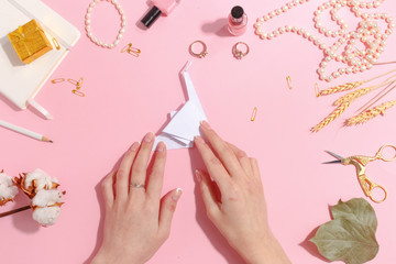 Girl makes paper crane origami. Top view.