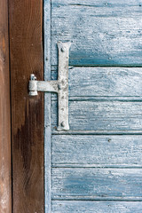 Close-up wood door in flaking blue paint in wood panel