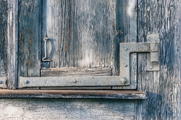 Dilapidated blue wood window shutter with metal hinge and latch