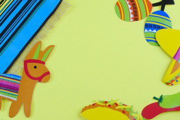 Cinco de Mayo image with copy space on yellow background surrounded by colorful party props with Mexican themed subjects