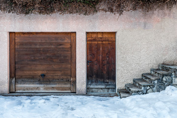 Weather-worn wood garage and entry doors in stone outbuilding
