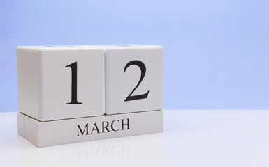 March 12st. Day 12 of month, daily calendar on white table with reflection, with light blue background. Spring time, empty space for text