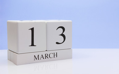 March 13st. Day 13 of month, daily calendar on white table with reflection, with light blue background. Spring time, empty space for text