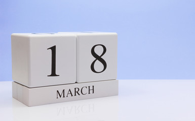 March 18st. Day 18 of month, daily calendar on white table with reflection, with light blue background. Spring time, empty space for text