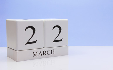 March 22st. Day 22 of month, daily calendar on white table with reflection, with light blue background. Spring time, empty space for text