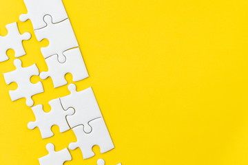 White jigsaw puzzle on vivid yellow background with copy space using for thinking strategy for business solution, teamwork, connection or idea for success