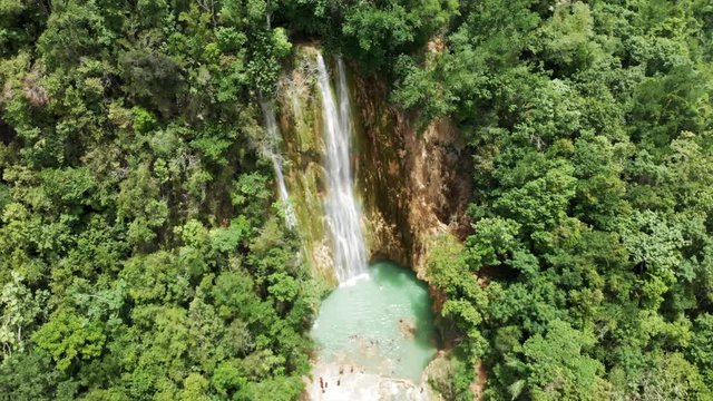 Aerial: People Bathing in Natural Pool under Scenic Waterfall Among Lush Green