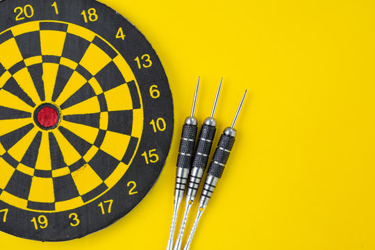 Flat Lay Of Perfect Black Darts With Dartboard On Solid Yellow Background With Copy Space Using As Target And Goals Or Three Best Important Things You Need To Know Concept