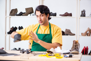Young man repairing shoes in workshop