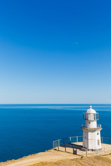 Fototapeta na wymiar White lighthouse on a background of blue sea