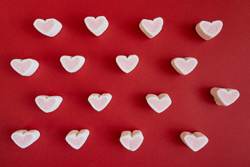 Marshmallow in the form of hearts on red background. Valentine's Day.