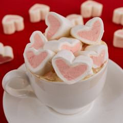 Pink sweet marshmallow hearts in a cup on the red background. Valentine's day background