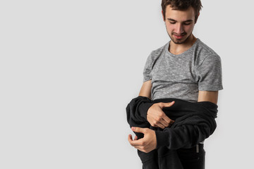 Tired caucasian young man happily removes his clothes after long and busy day. Isolated on white background.