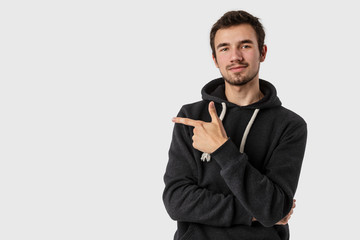 Satisfied caucasian young man pointing at blank space and looking into the camera. Isolated on white background. Advertisement concept.