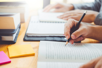 High school or college students studying and reading together in library