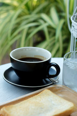 Well mixed black hot black coffee in black coffee cup on wood table served in a restaurant in a coffee break time, popular drink for meeting place and party time, value added design for better sales