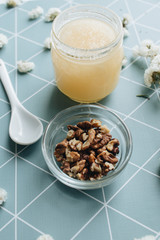 Honey with spoon and white flowers on table