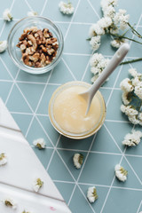 Honey with spoon and white flowers on table