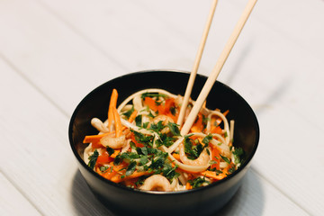 Delicious meal of different ingredients, egg, shrimps, tomatoes, carrot, lettuce, sesame seeds and seaweed in black plate, Asian cuisine 