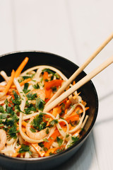 Delicious meal of different ingredients, egg, shrimps, tomatoes, carrot, lettuce, sesame seeds and seaweed in black plate, Asian cuisine 