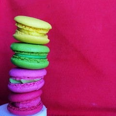 A stack of macaron. They're colorful with red background.