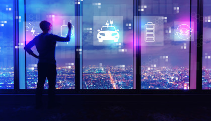 EV with man writing on large windows high above a sprawling city at night