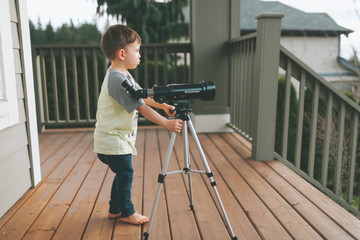 A little boy setting up a telescope. 