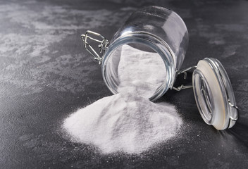 Jar of baking soda on a black background.