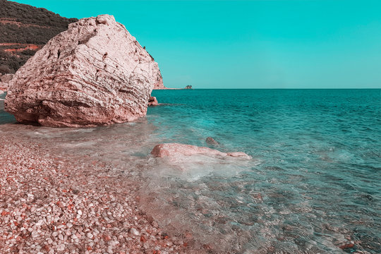 Panoramic view of pebble beach with clear azure blue water and layered rocks, beautiful mediterranean Adriatic Sea coast, Montenegro