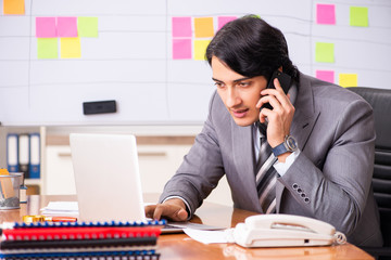 Young handsome employee working in the office
