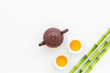 Asian tea traditions. Drink tea. Tea ceremony. Tea pot near cups of green tea and bamboo decoration on white background top view space for text