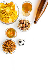 Snacks for watching football on TV. Watching sports. Chips, nuts, rusks near beer and soccer ball on white background top view copy space