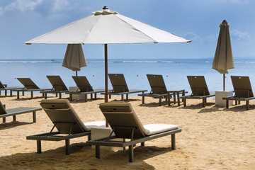 Empty beach chairs and umbrellas on a beach of Sanur in Bali, Indonesia