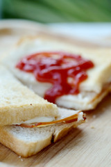Ham cheese sandwich and tomato ketchup on wood tray and space for write wording, easy delicious food served with coffee or tea in coffee shop or office, popular food for office worker, time saving