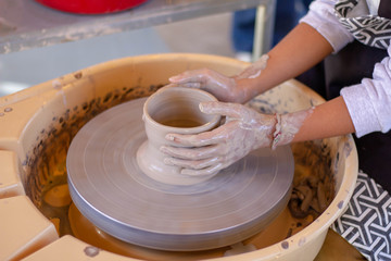 Fototapeta premium Close-up detail view at an artist makes clay pottery on a spin wheel.
